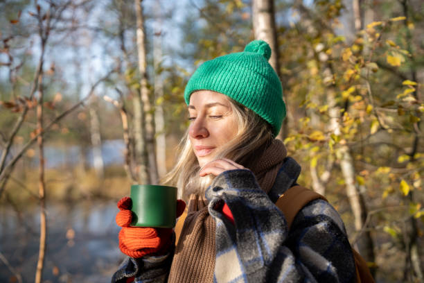 Person enjoying herbal tea mindfully in a Norwegian forest setting